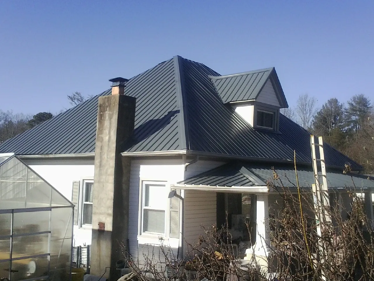 Dark blue standing seam metal roof on a white farmhouse with dormer — Slate & Tile Roof Repair by Roofing Brothers in Coos Bay