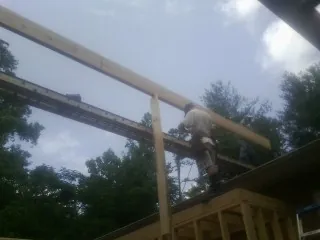 Carpenter setting a ridge beam over a new addition frame — Ice Dam Removal by Roofing Brothers in Coos Bay