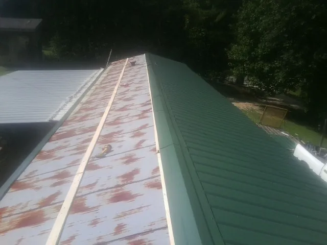 Old rusted panels beside newly installed green metal roofing — Wind Damage Roof Repair by Roofing Brothers in Coos Bay