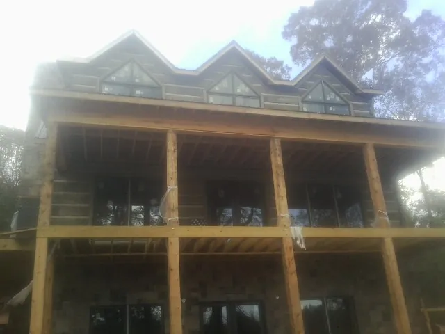 Dormers and porch framing on a large log home under construction — Roof Coating work by our crew in Coos Bay