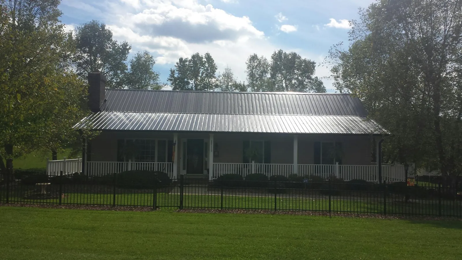 Gray metal roof on a brick ranch with a full width front porch — Gutter Guard Installation work by our crew in Coos Bay