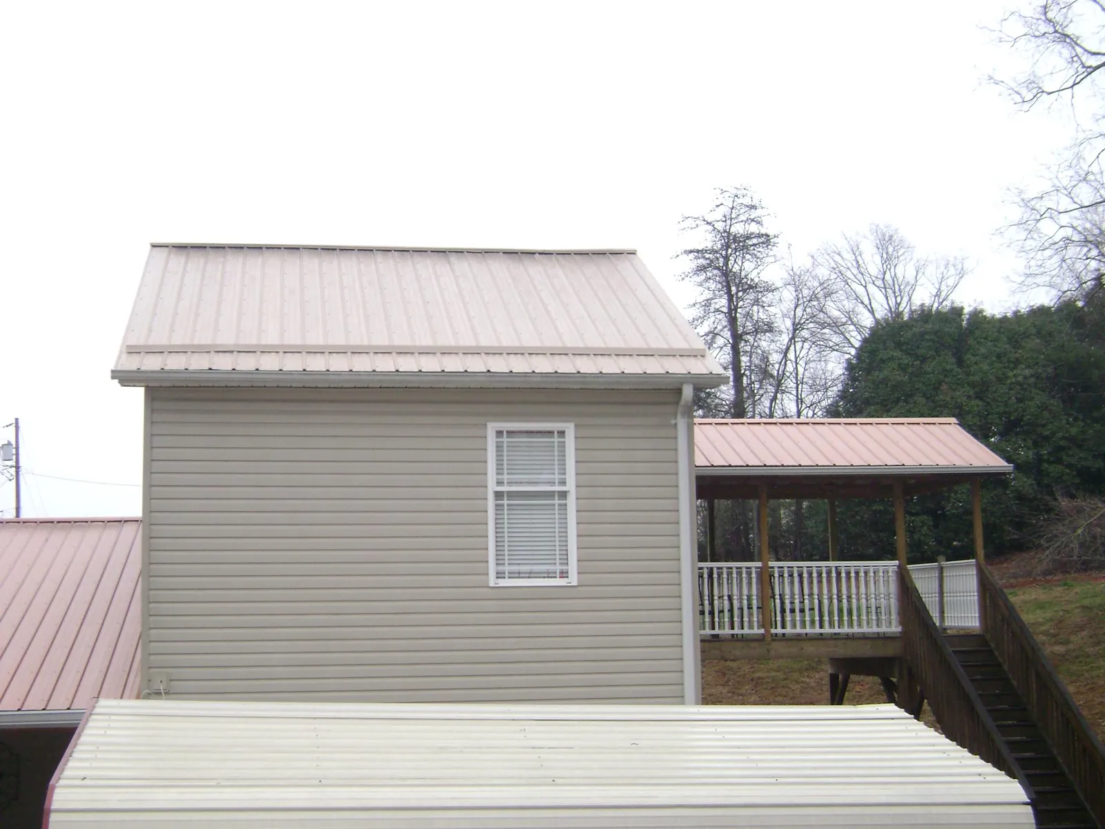 Tan metal roofs on a two story addition and attached porch, from a Roof Replacement job in Coos Bay