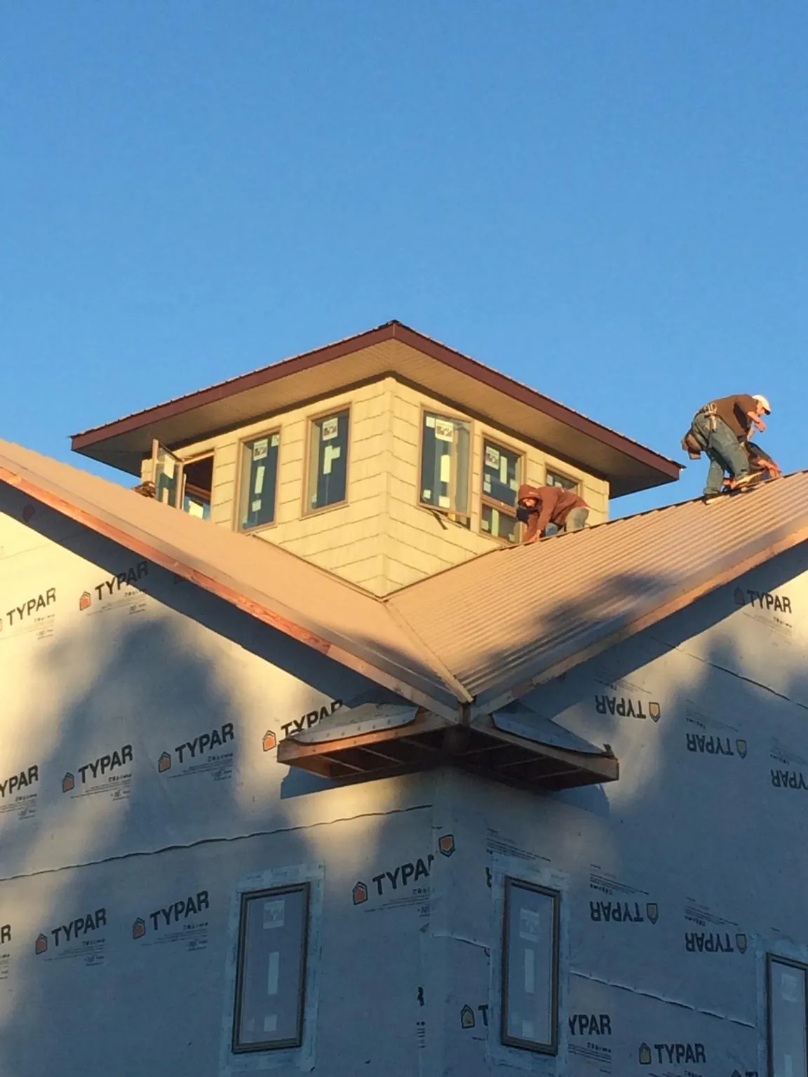 Roofers working around a rooftop cupola on a new metal roof at sunset — Roof Waterproofing in Coos Bay by Roofing Brothers